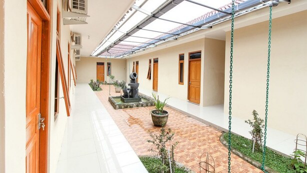 A corridor with a tiled floor, potted plants, and a statue. - RedDoorz near Balekambang City Park (Surakarta)