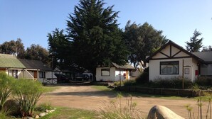 A rustic lodge with a dirt driveway, surrounded by greenery and large trees. - Mantagua Village (Quintero)