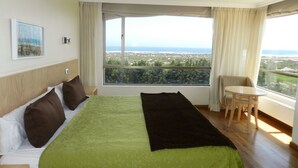 A hotel room with a bed, a view of the city, a small table, and a chair. - Mantagua Village (Quintero)