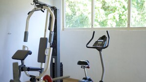 Une salle de sport équipée de matériel d’exercice, notamment un banc de musculation et un appareil elliptique.