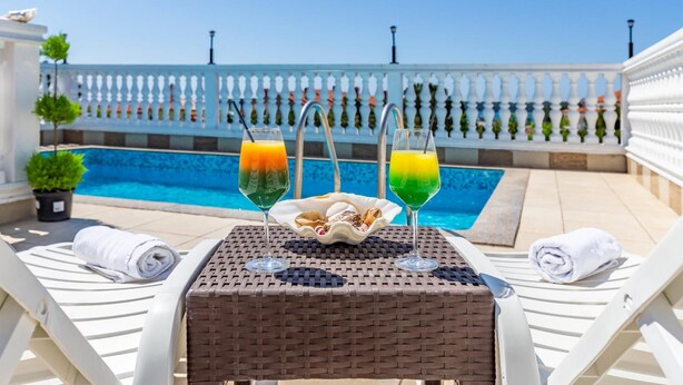 A poolside table with two drinks, a bowl of snacks, and towels. - Villa San Rocco Bed&Breakfast (Medulin)