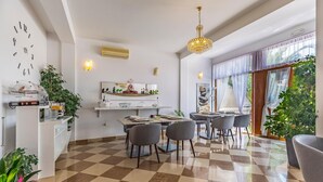 A dining area with a checkered floor, a chandelier, and a large window with sheer curtains. - Villa San Rocco Bed&Breakfast (Medulin)