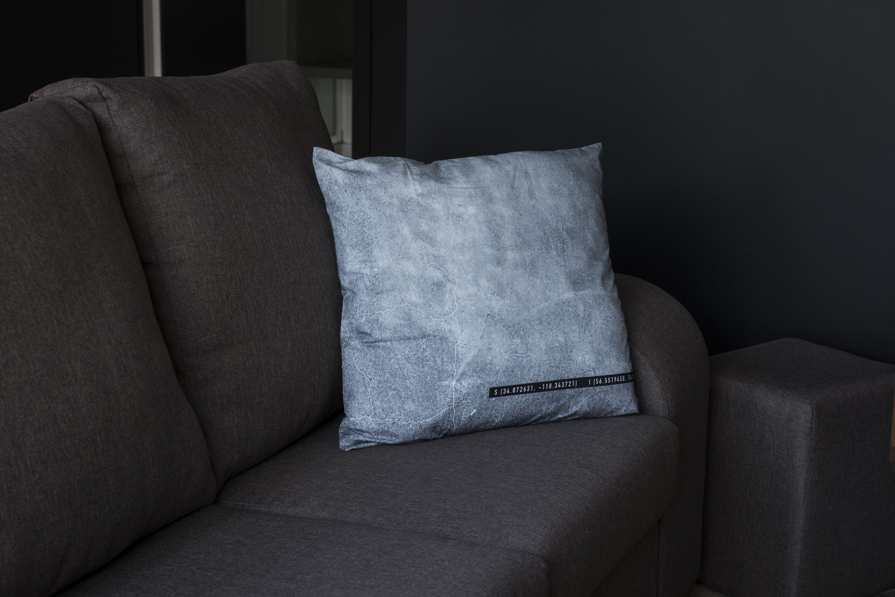 Ein graues Sofa mit einem strukturierten grauen Kissen.