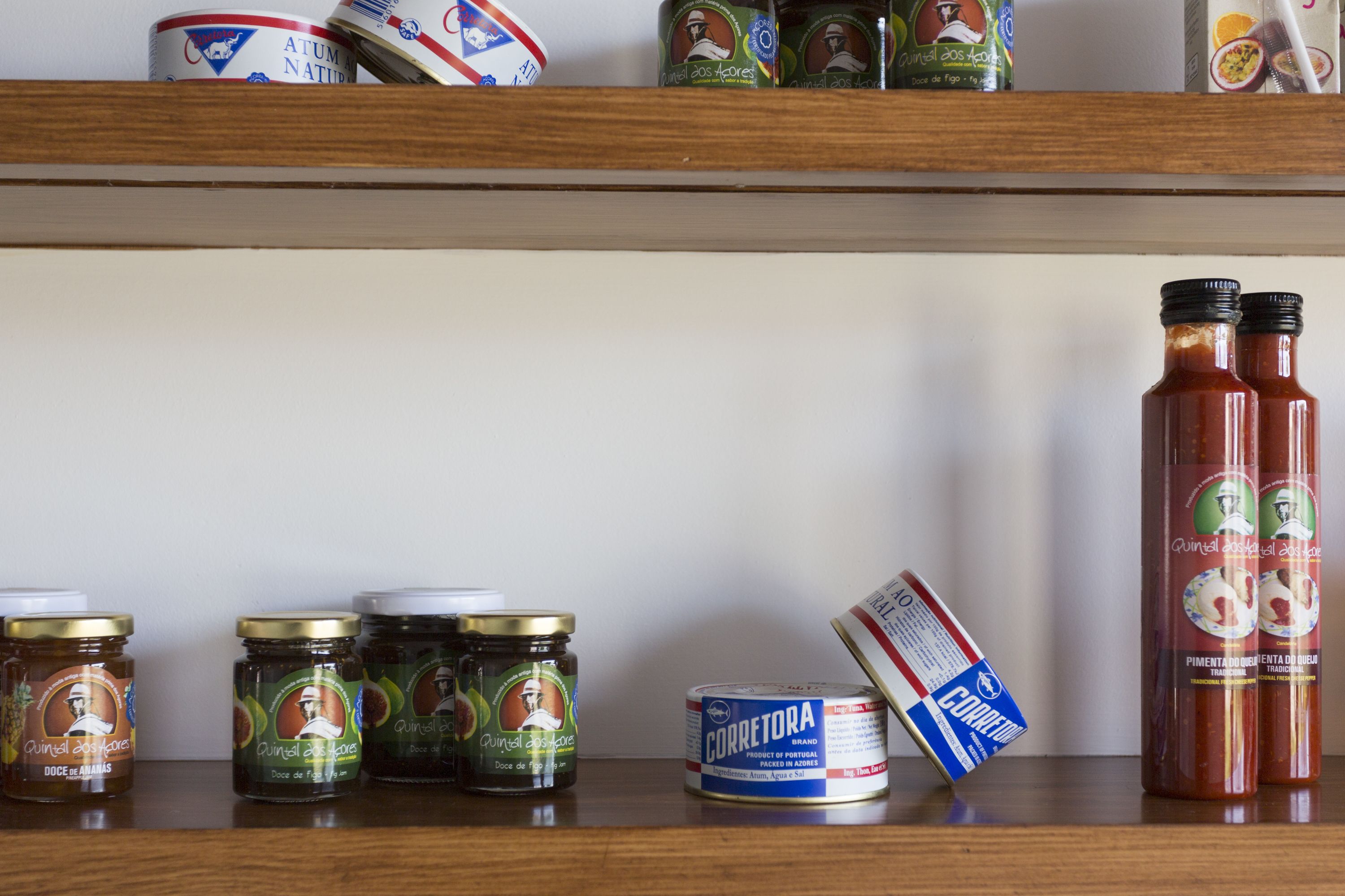 A shelf with various food items including jars, cans, and a bottle.