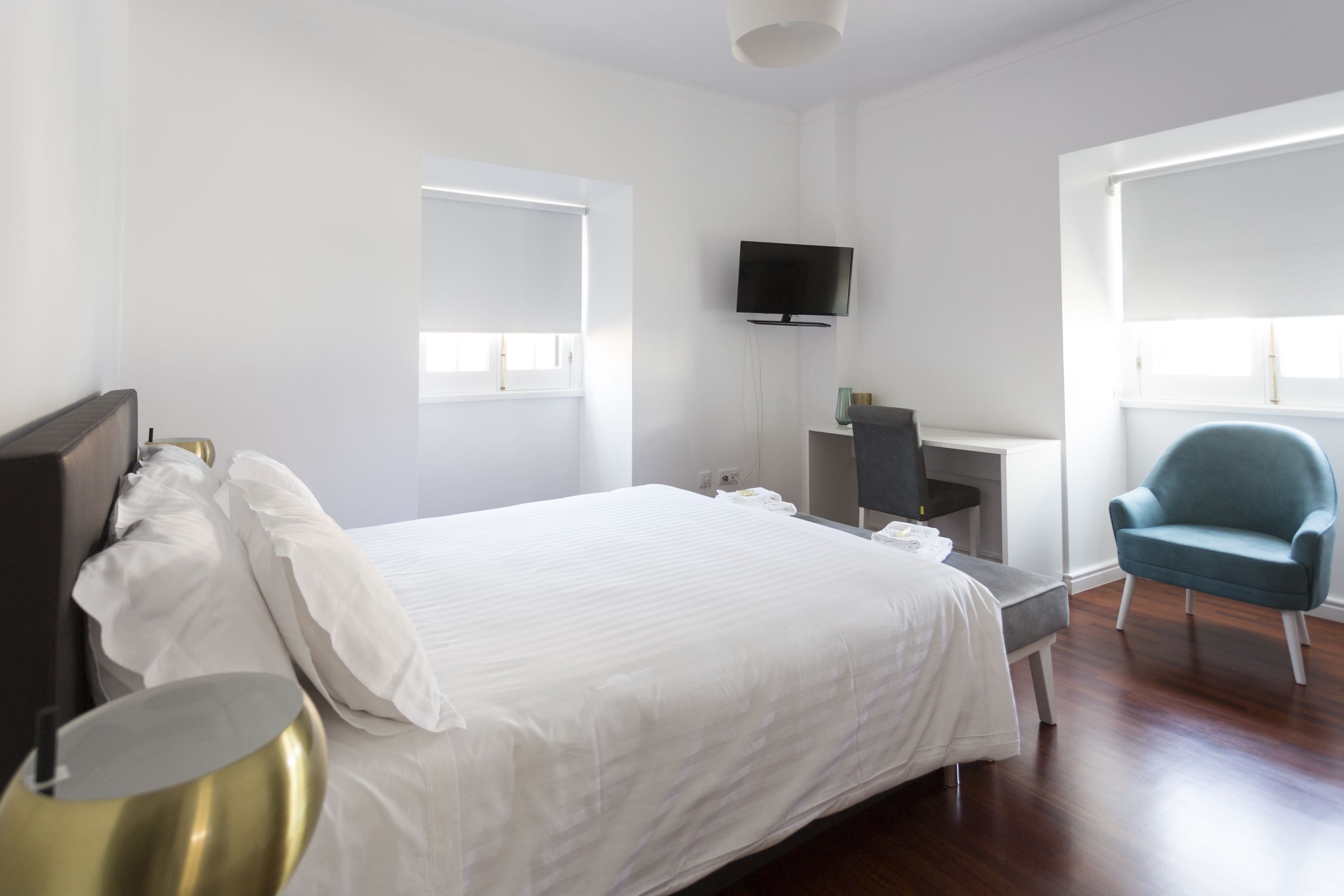 A hotel room with a large bed, a desk, a TV, and a chair.