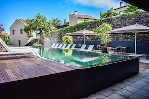 Una piscina al aire libre, sillones reclinables de piscina