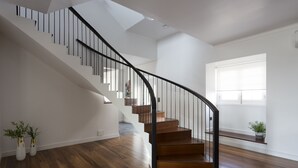 A modern staircase with wooden steps and black railings, leading to a second floor. - Volcanic Charming House (Ribeira Grande)