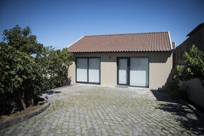 A modern house with a tiled roof, large windows, and a cobblestone driveway. - Volcanic Charming House (Ribeira Grande)
