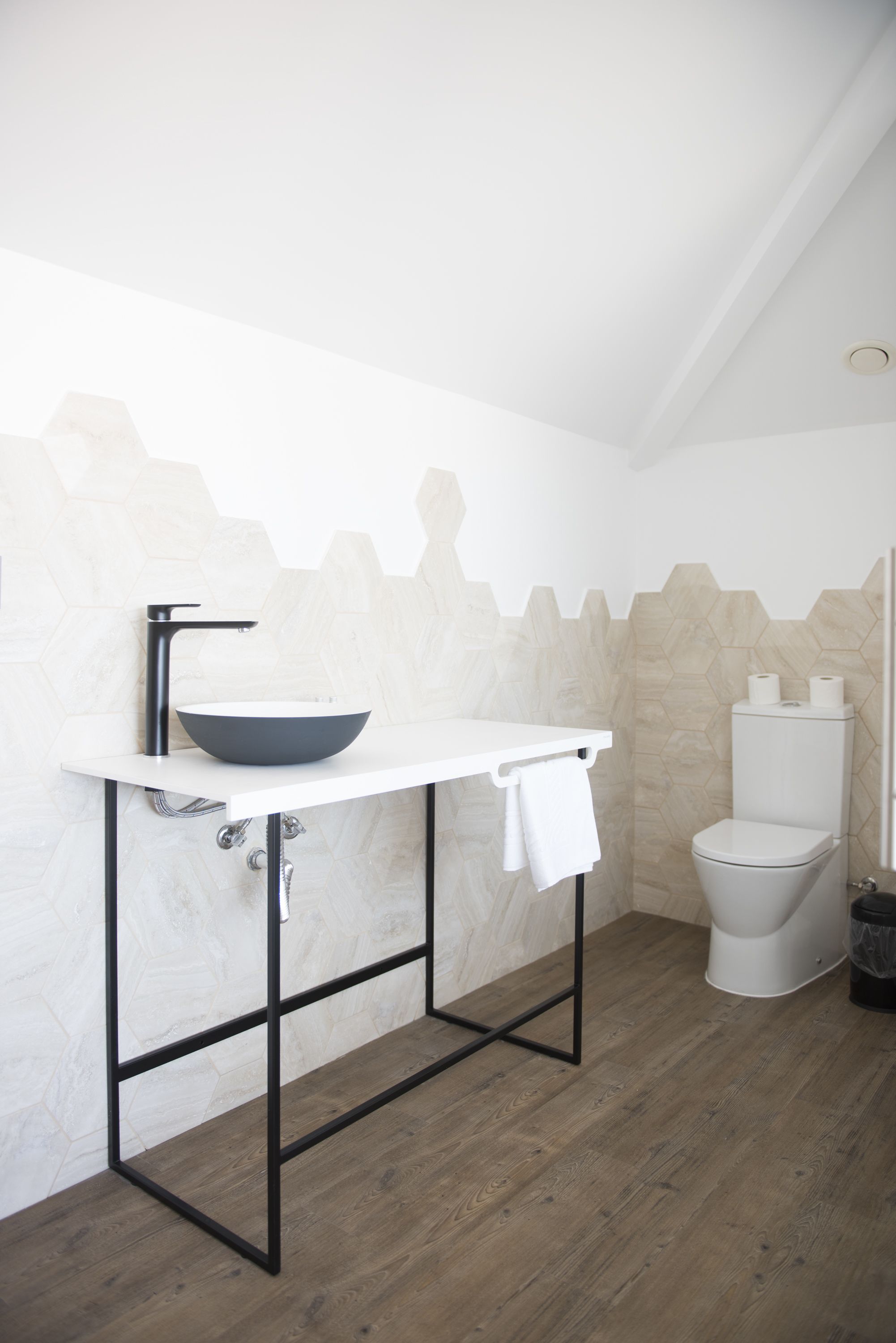 A modern bathroom with a white sink, black faucet, and a white toilet.