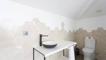 Un baño moderno con un lavamanos blanco, un grifo negro y un inodoro.
