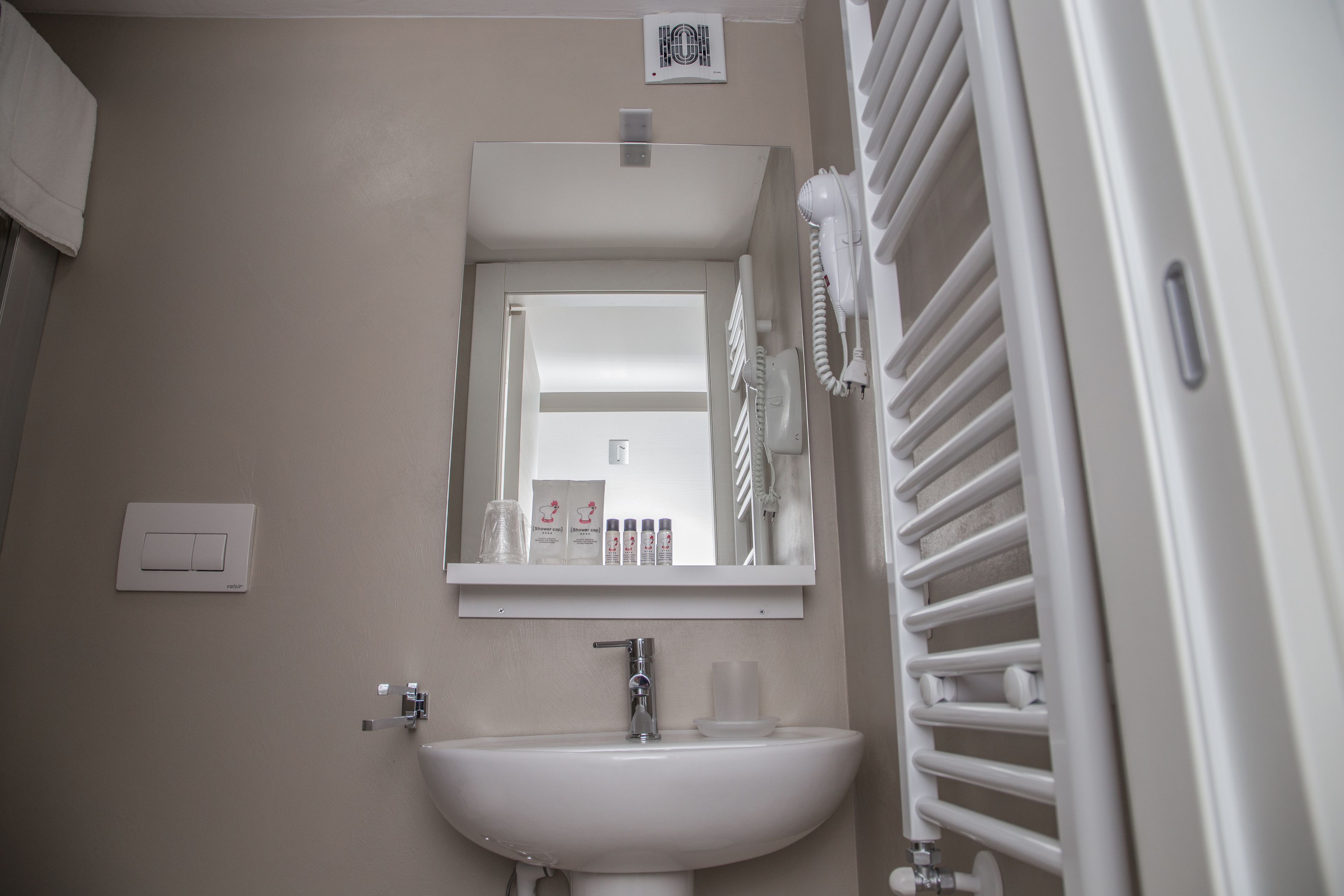 A bathroom with a white sink, a mirror, a towel rack, and a heater.
