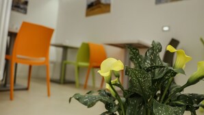 A room with a plant, orange and green chairs, and a table. - La Civita B&B (Gravina in Puglia)
