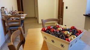 A dining area with a wooden table and chairs, a decorative box with Christmas ornaments, and a door with a sign. - Azienda Agrituristica Lavagè (Rossiglione)
