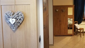 A room with a wooden wardrobe, a heart-shaped decoration, and a bed with a headboard. - Azienda Agrituristica Lavagè (Rossiglione)