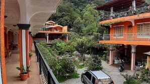 A hotel with a covered balcony, a stone courtyard, and a mountainous backdrop. - Posada de Don Jose (Panajachel)