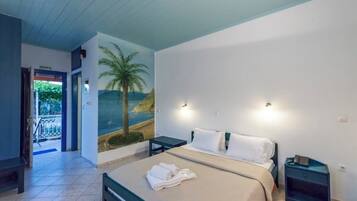 A hotel room with a bed, a nightstand, a wall mural, a door to the outside, and a small table.