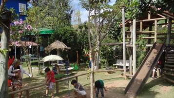 A playground with slides, climbing structures, and a thatched-roof shelter.
