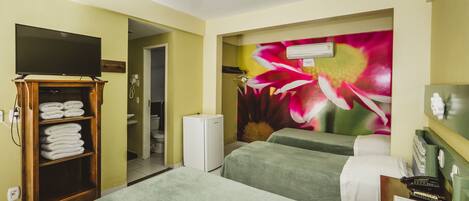Habitación de hotel con dos camas, televisión, refrigerador y un mural floral en la pared.