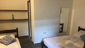 A hotel room with two beds, a mirror, a shelf with toiletries, and a tiled floor.