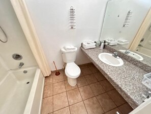 Et badeværelse med badekar, toilet og granitbordplade med to vaske.