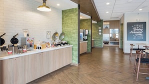 A modern kitchen area with a counter, waffle maker, coffee station, and a view into a dining area. - Fairfield Inn & Suites by Marriott Dallas Plano/Frisco (Plano)