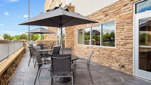 An outdoor patio with stone walls, a stone floor, and a seating area with tables and chairs. - Fairfield Inn & Suites by Marriott Dallas Plano/Frisco (Plano)