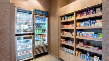 A snack and beverage vending area with multiple shelves stocked with various brands and types of snacks and drinks.