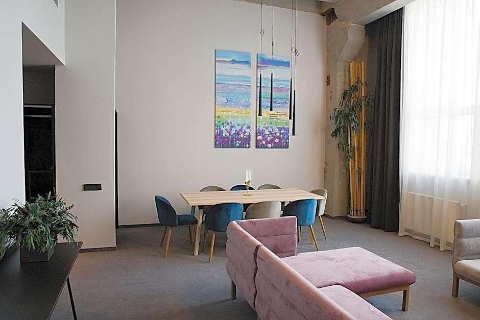 Ein modernes Wohnzimmer mit Esstisch, Stühlen, einem rosafarbenen Sofa und zwei Bildern an der Wand.