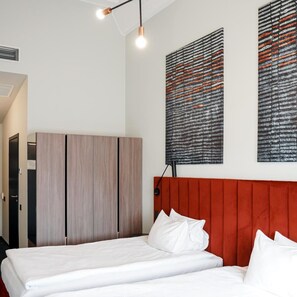 A modern bedroom with a bed, a wardrobe, and two abstract paintings on the wall. - Loop Hotel Vilnius (Vilnius)