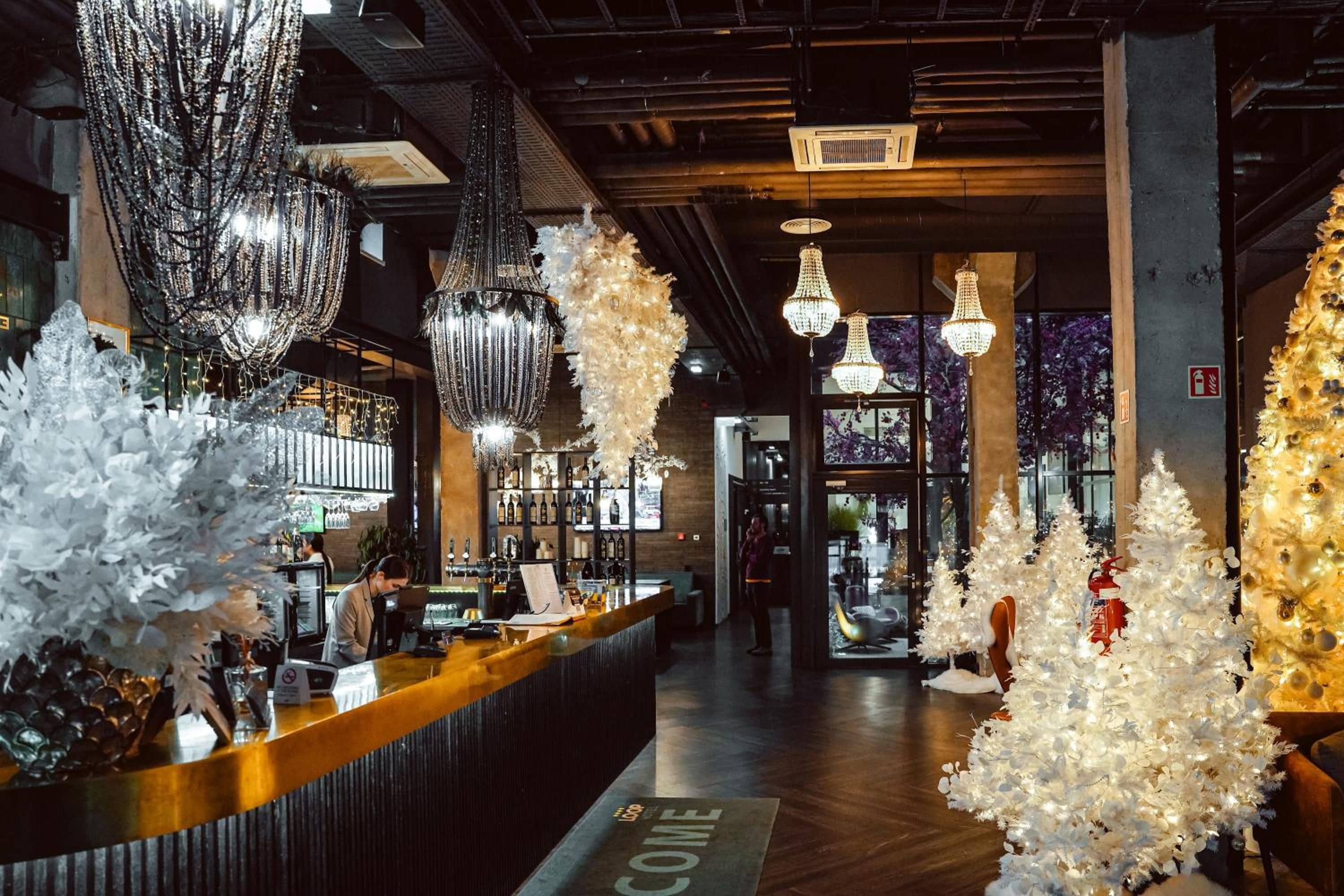 Una zona de bar con mostrador, luces decorativas y árboles de Navidad blancos.