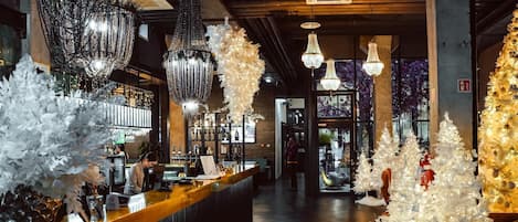 Una zona de bar con mostrador, luces decorativas y árboles de Navidad blancos.