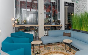 A modern interior with a blue sofa, two round tables, and a patterned rug. - Loop Hotel Vilnius (Vilnius)