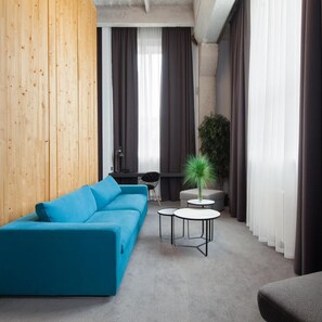 Una sala de estar moderna con un sofá azul, una mesita redonda y una planta en maceta.