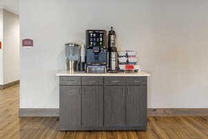 Una estación de café con una máquina de café, un molinillo y un dispensador de café.