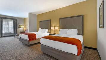 Une chambre d’hôtel avec deux lits, un bureau et une chaise.