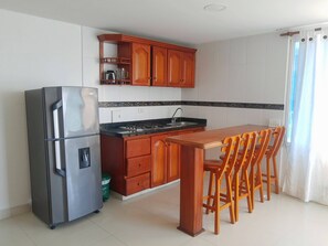 A compact kitchen with a refrigerator, stove, and wooden cabinets.