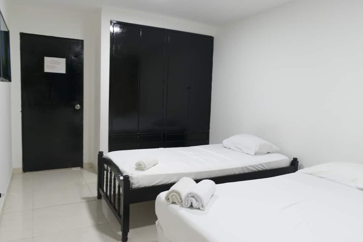 A room with two beds, a black wardrobe, and a door with a sign.