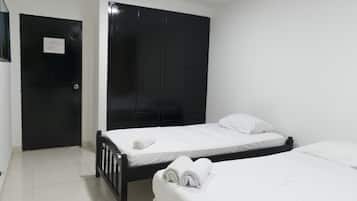 A room with two beds, a black wardrobe, and a door with a sign.