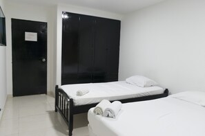 A room with two beds, a black wardrobe, and a door with a sign.