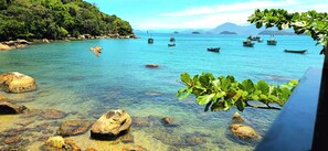 A coastal scene with clear water, rocks, and boats. - Pousada Sobre As Ondas De Picinguaba (Ubatuba)