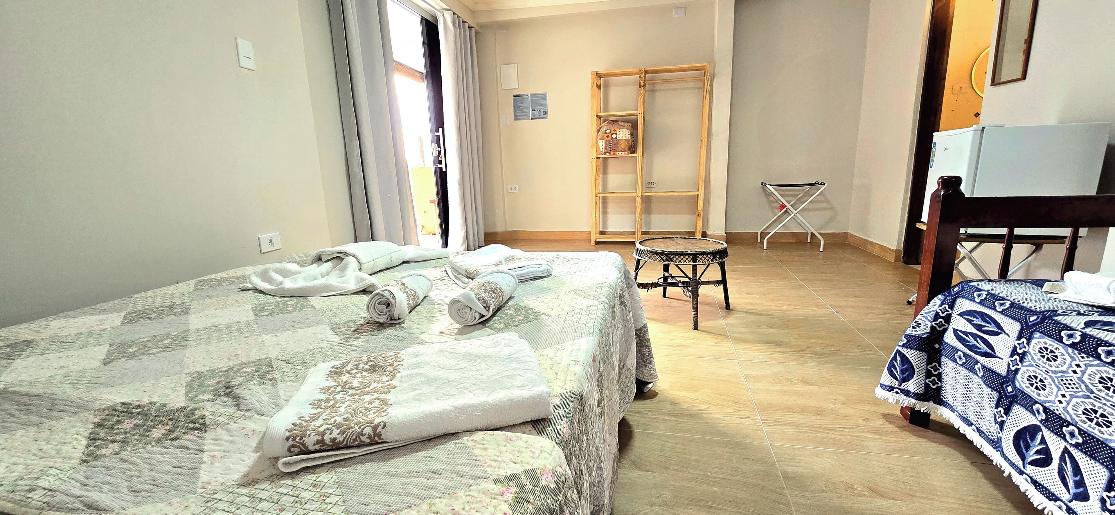 Een slaapkamer met een bed, een stoel, een klein tafeltje en een kledingkast.