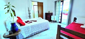 A hotel room with a bed, a small table with a vase and a remote control, a dresser, and a window with curtains. - Pousada Sobre As Ondas De Picinguaba (Ubatuba)