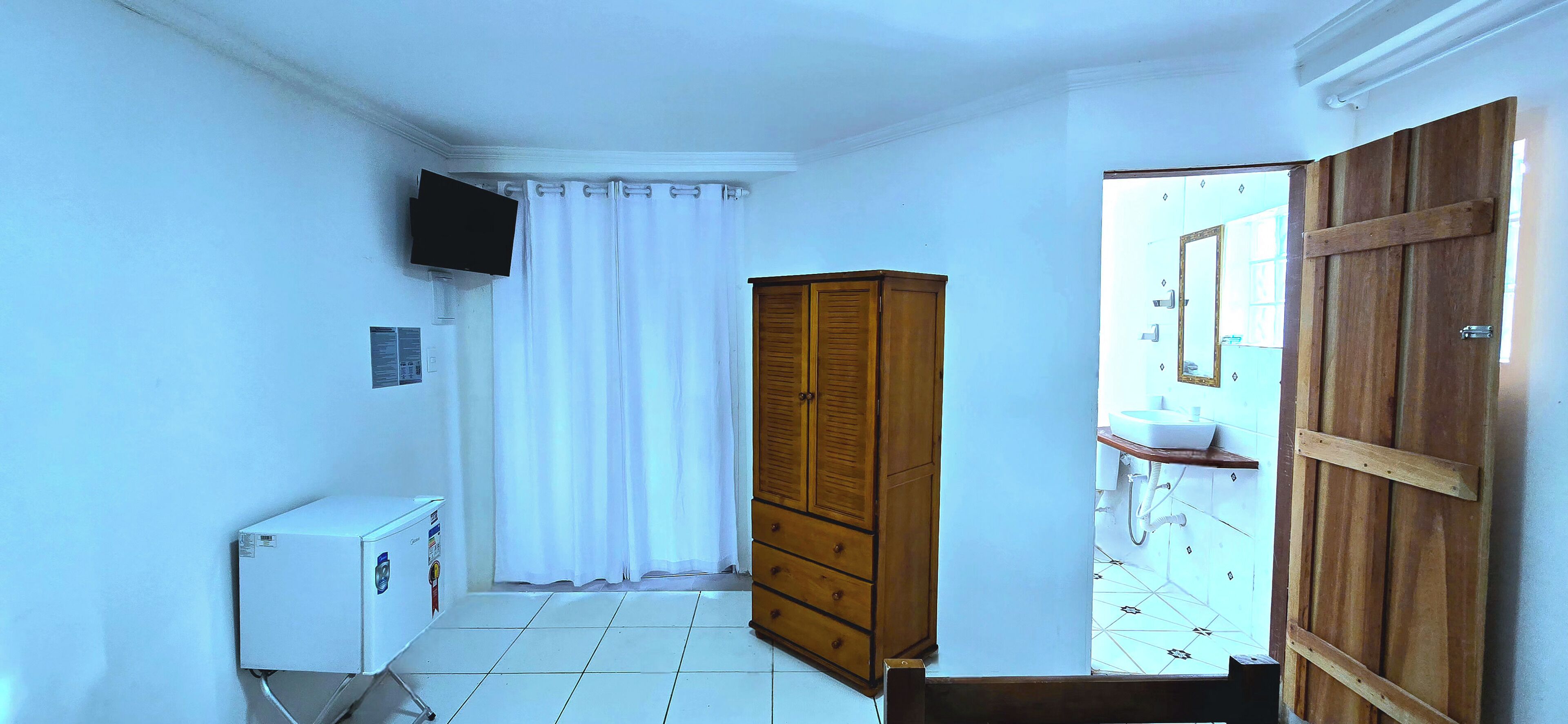 Un baño pequeño y limpio con un armario de madera, un inodoro blanco y una zona de ducha.