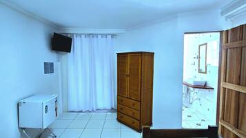 Un baño pequeño y limpio con un armario de madera, un inodoro blanco y una zona de ducha.