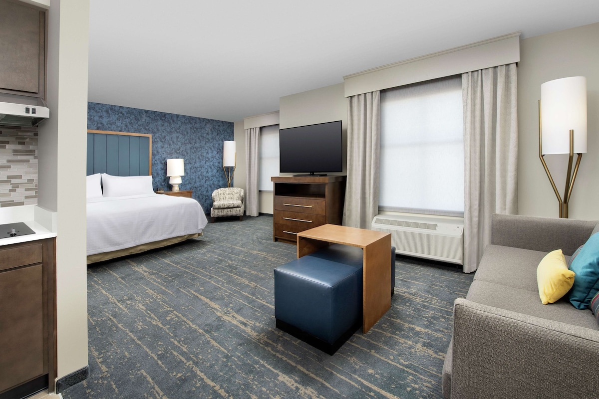 Habitación de hotel con cama, televisor, sofá, mesita, silla y escritorio.