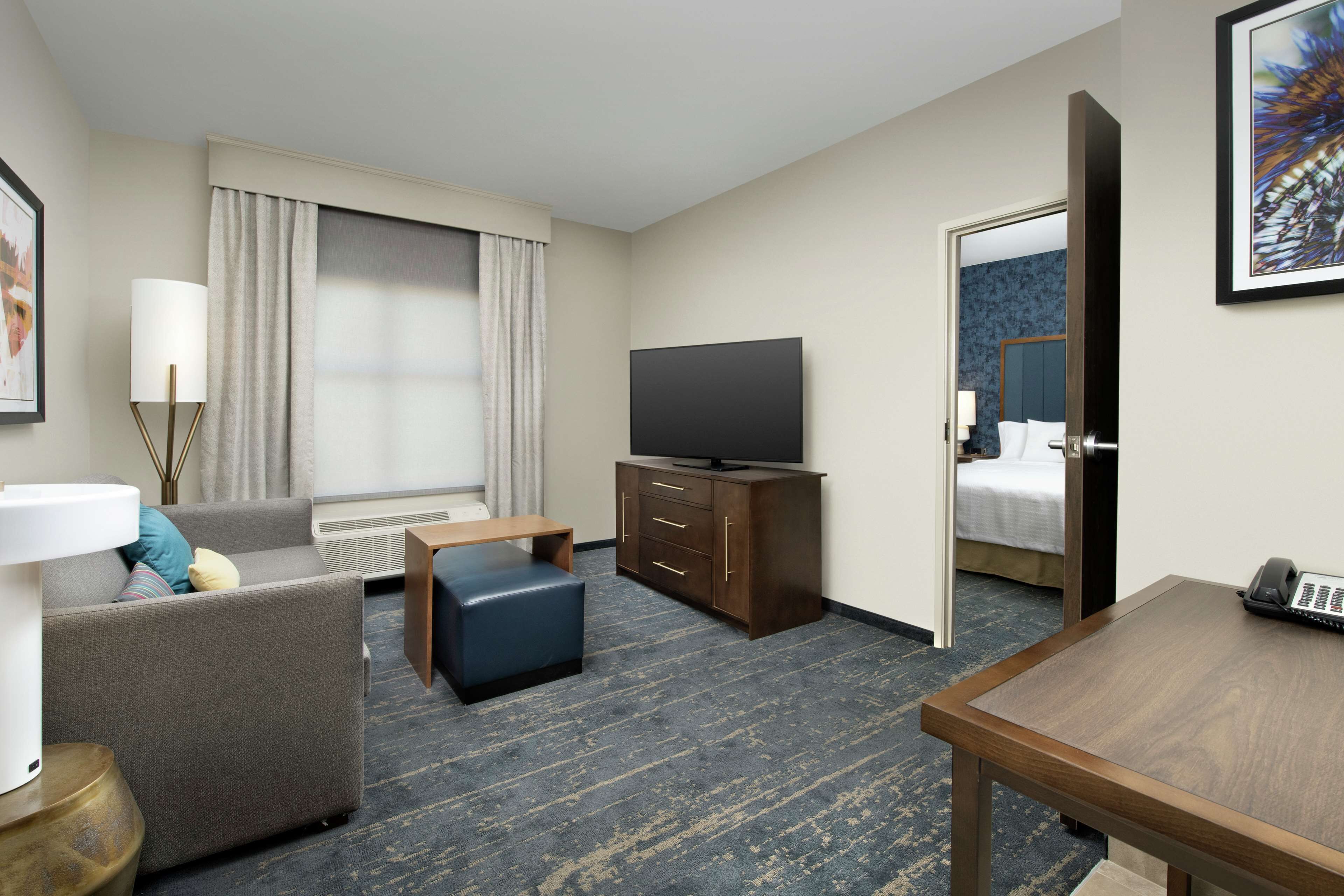 Una habitación de hotel con sofá, una pequeña mesa, televisor, escritorio y cama.