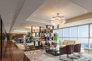 Ein geräumiger Wohnbereich mit hohen Decken, einer großen Chandelier und Blick durch große Fenster.