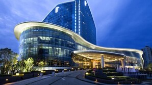 Un hotel moderno con fachada de vidrio curva y una torre destacada.