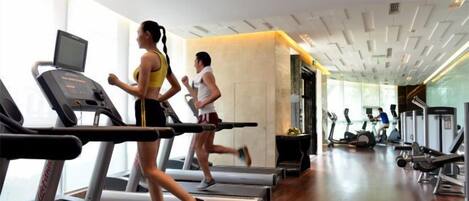 A gym with treadmills, a television, and exercise equipment.