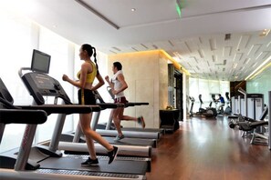 Une salle de sport équipée de tapis de course, d’un téléviseur et d’appareils d’exercice.
